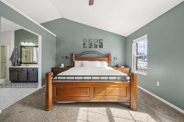 carpeted bedroom with ensuite bath, vaulted ceiling, a ceiling fan, and baseboards