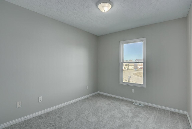 carpeted spare room featuring visible vents, a textured ceiling, and baseboards