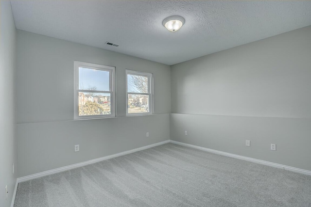 empty room featuring visible vents, baseboards, carpet, and a textured ceiling