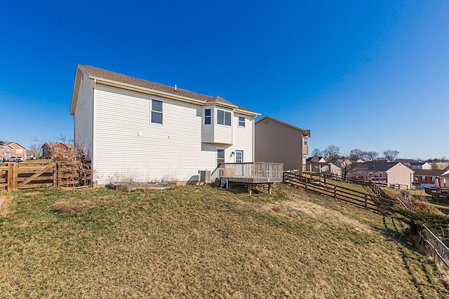 back of house with a fenced backyard, a lawn, and a wooden deck