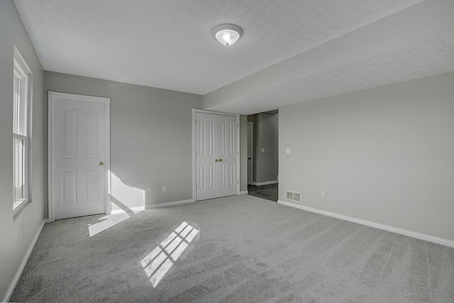 unfurnished bedroom with visible vents, a textured ceiling, baseboards, and carpet floors