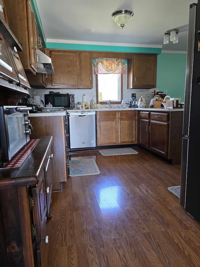 kitchen with tasteful backsplash, light countertops, exhaust hood, dark wood-style floors, and stainless steel appliances