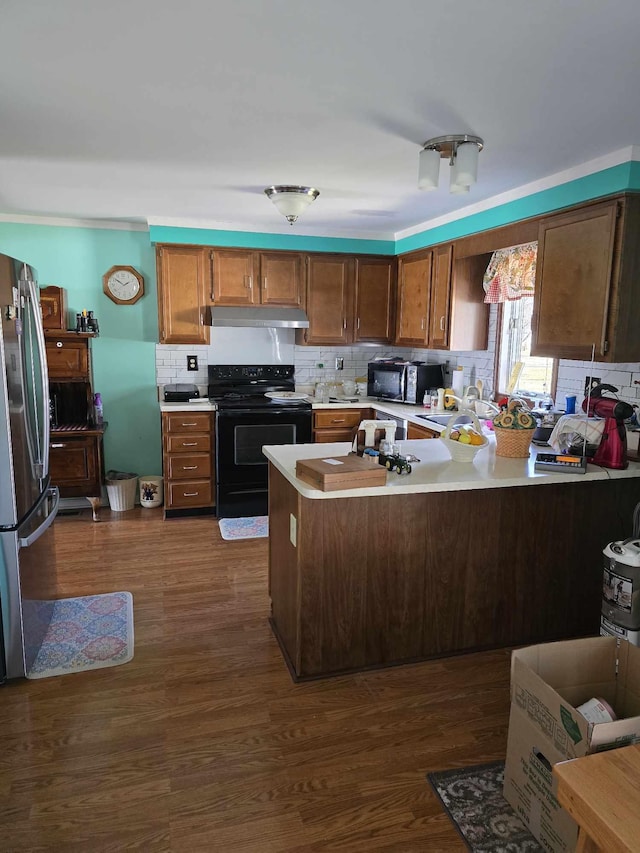 kitchen with a peninsula, black appliances, light countertops, dark wood-type flooring, and tasteful backsplash