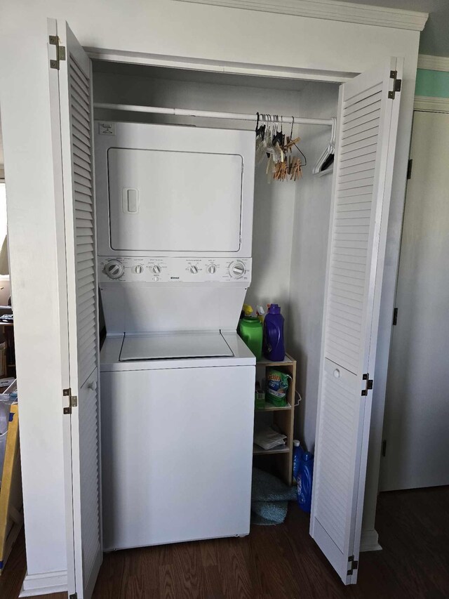 laundry room featuring stacked washer and dryer, wood finished floors, and laundry area