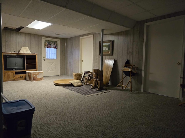 interior space with wooden walls, carpet, and a drop ceiling