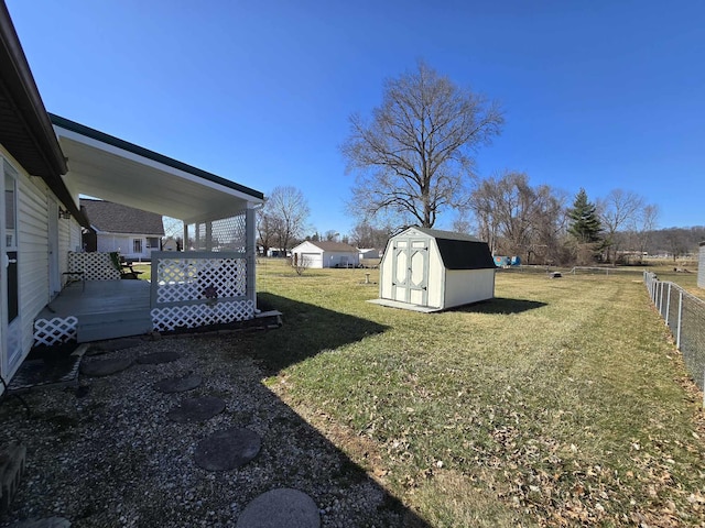 view of yard featuring a storage shed, fence, an outdoor structure, and a wooden deck