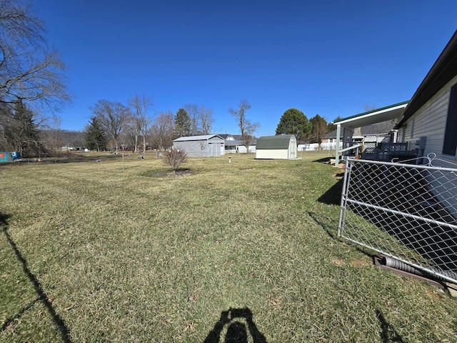 view of yard featuring an outbuilding, a storage unit, and fence