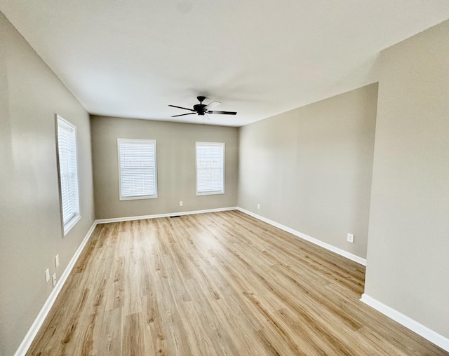 spare room featuring light wood finished floors, ceiling fan, and baseboards