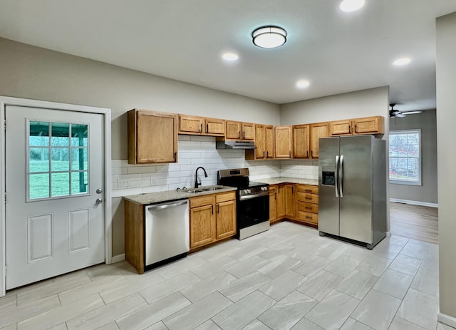 kitchen with a sink, tasteful backsplash, appliances with stainless steel finishes, and under cabinet range hood