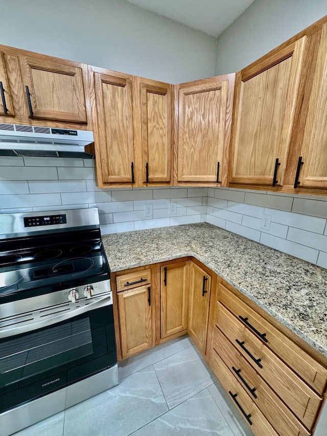 kitchen with under cabinet range hood, stainless steel electric range oven, light stone countertops, and tasteful backsplash