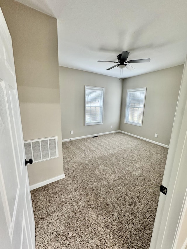 spare room featuring visible vents, baseboards, carpet, and a ceiling fan