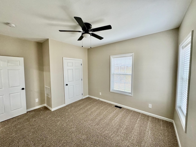 unfurnished bedroom featuring visible vents, baseboards, carpet floors, and ceiling fan