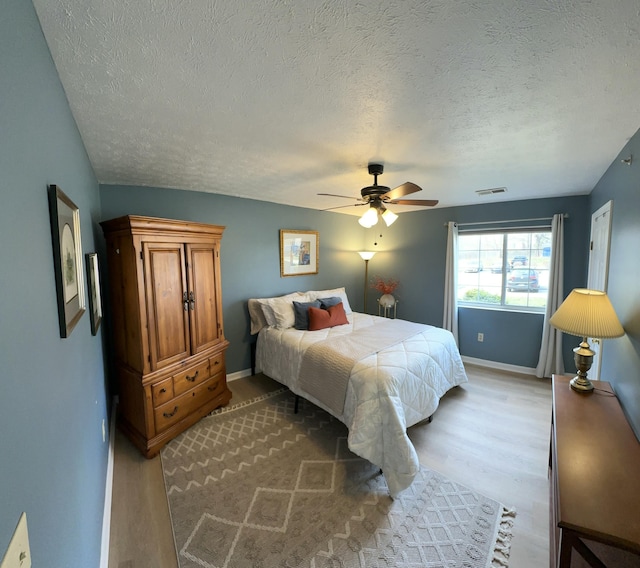 bedroom with visible vents, a ceiling fan, baseboards, and wood finished floors