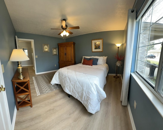 bedroom with a ceiling fan, baseboards, and light wood-type flooring