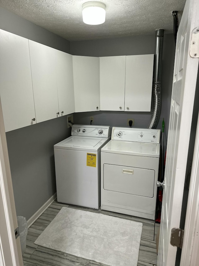 washroom featuring light wood-style floors, cabinet space, a textured ceiling, and independent washer and dryer