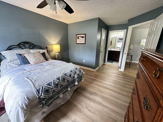 bedroom featuring a ceiling fan, baseboards, light wood finished floors, and connected bathroom