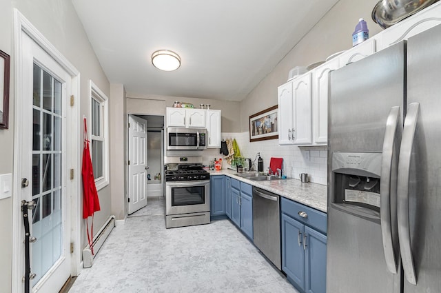 kitchen with a baseboard heating unit, light countertops, appliances with stainless steel finishes, white cabinets, and blue cabinets