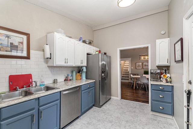 kitchen featuring blue cabinetry, appliances with stainless steel finishes, white cabinets, and a sink