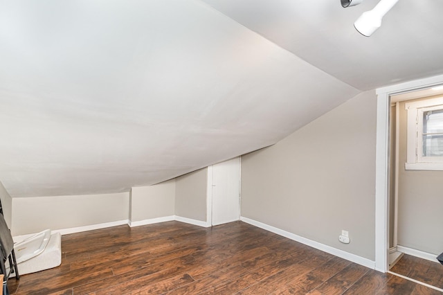 additional living space featuring baseboards, dark wood-style floors, and vaulted ceiling