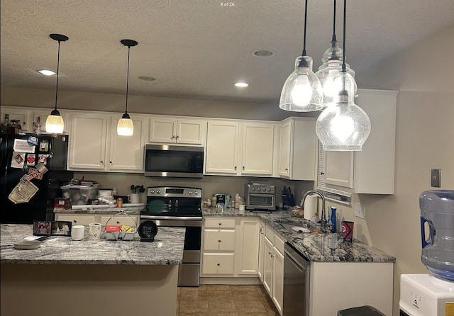 kitchen featuring a sink, light stone counters, white cabinetry, and stainless steel appliances