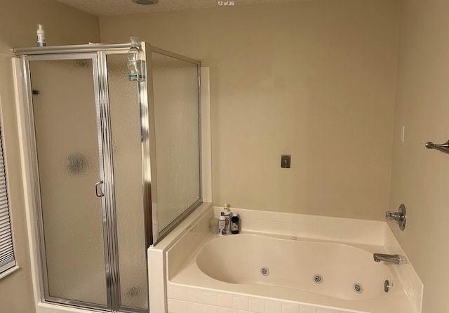 bathroom featuring a stall shower, a textured ceiling, and a whirlpool tub