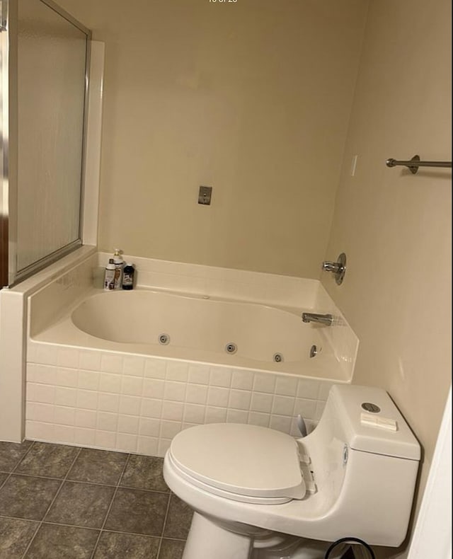 bathroom with tile patterned flooring, a tub with jets, and toilet