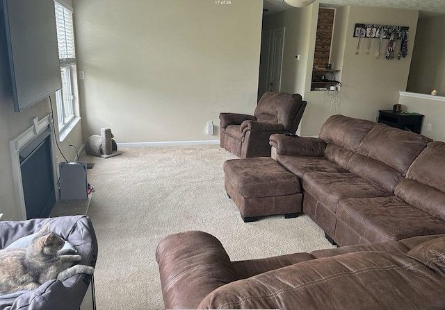 living area with baseboards, a fireplace, and carpet flooring