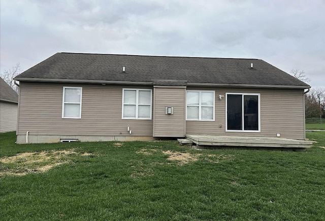 rear view of house featuring a lawn, roof with shingles, and a deck