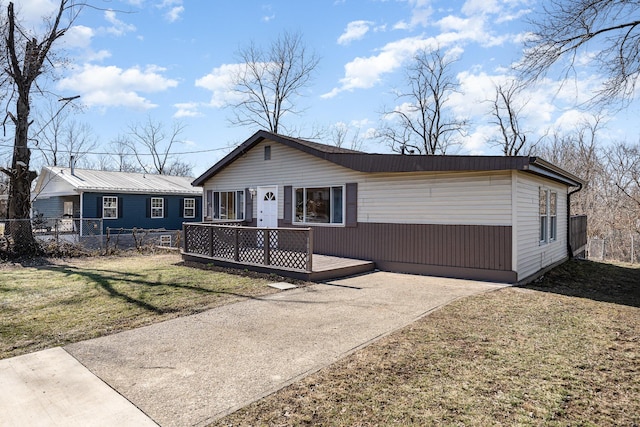 view of front of home featuring a front lawn, concrete driveway, fence, and a wooden deck