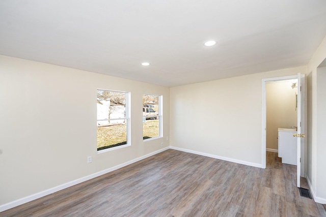 spare room featuring visible vents, recessed lighting, baseboards, and wood finished floors