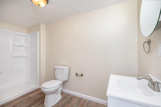 bathroom with toilet, vanity, baseboards, and wood finished floors