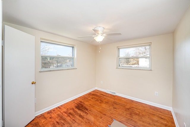 empty room featuring a ceiling fan, wood finished floors, baseboards, and visible vents