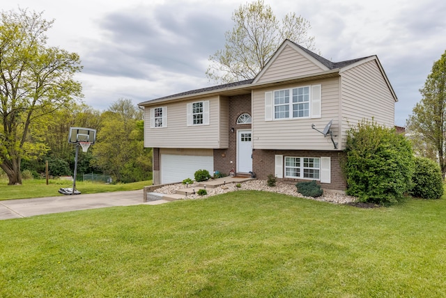 split foyer home featuring a front yard, an attached garage, brick siding, and driveway