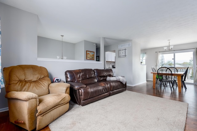 living room with visible vents, baseboards, dark wood-type flooring, and an inviting chandelier