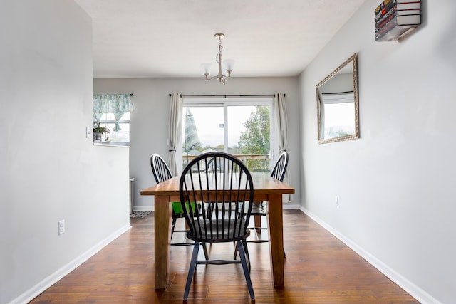 dining space featuring dark wood finished floors, baseboards, and a chandelier