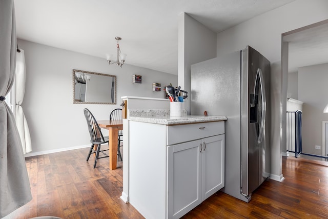 kitchen with a notable chandelier, dark wood finished floors, stainless steel fridge, light countertops, and baseboards