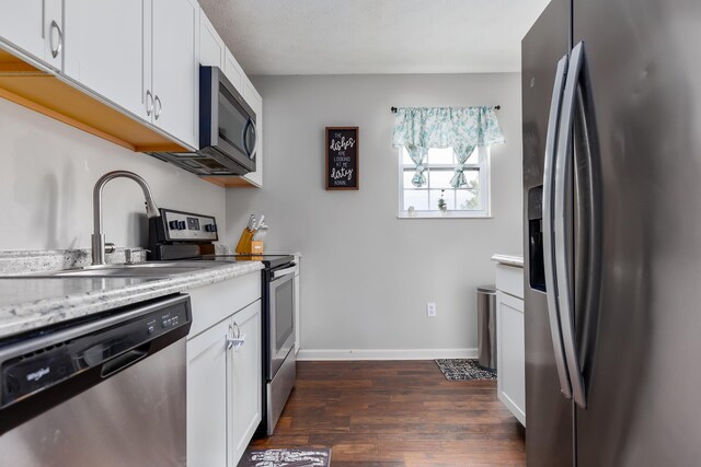 kitchen with dark wood finished floors, white cabinets, stainless steel appliances, and a sink