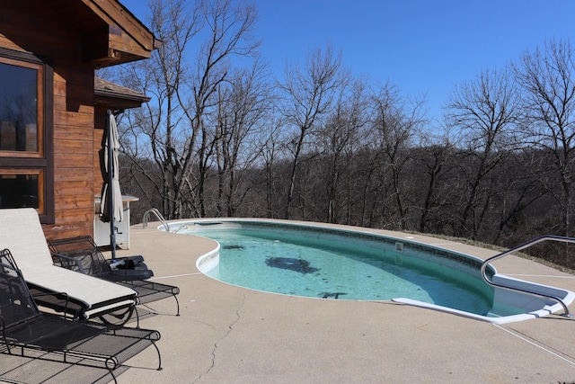 pool featuring a patio and a wooded view