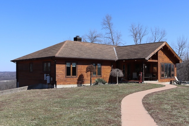 back of property with a chimney, a lawn, a shingled roof, and a sunroom