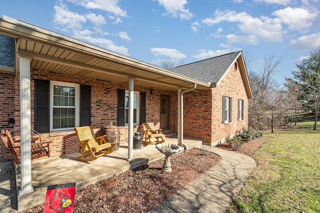 exterior space featuring a porch, brick siding, and roof with shingles