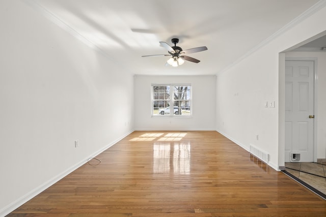 spare room with visible vents, baseboards, ceiling fan, ornamental molding, and wood finished floors