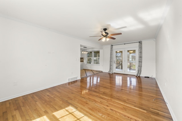 empty room featuring visible vents, baseboards, ornamental molding, wood finished floors, and a ceiling fan