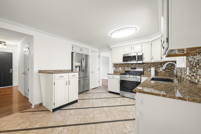 kitchen with a sink, tasteful backsplash, appliances with stainless steel finishes, and light tile patterned floors