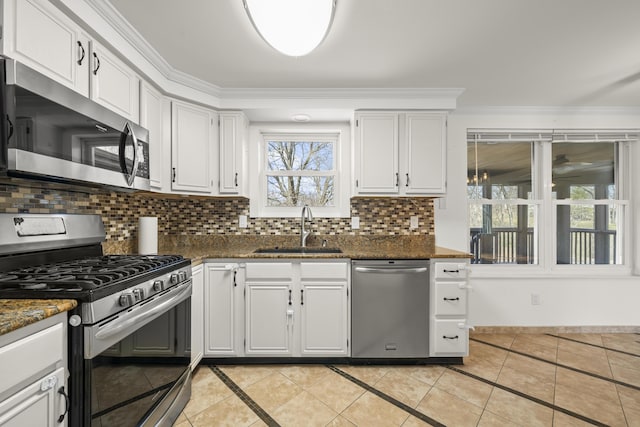 kitchen with a sink, decorative backsplash, ornamental molding, stainless steel appliances, and white cabinetry