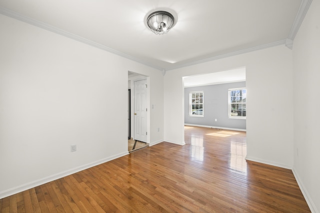 spare room featuring hardwood / wood-style flooring, baseboards, and ornamental molding