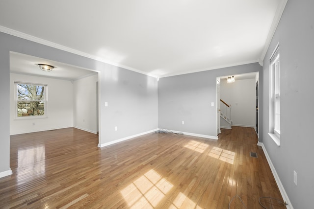 spare room featuring stairs, baseboards, light wood finished floors, and ornamental molding