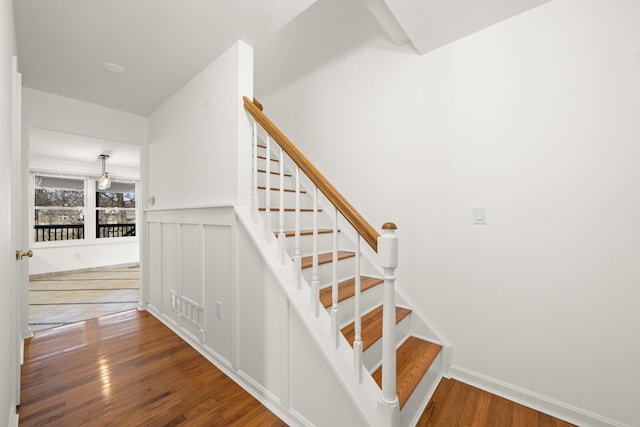 stairs with visible vents, hardwood / wood-style floors, wainscoting, and a decorative wall