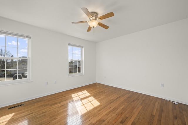 unfurnished room with hardwood / wood-style flooring, baseboards, visible vents, and ceiling fan