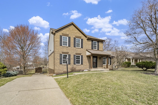 view of front of house featuring brick siding, driveway, a front yard, and a gate