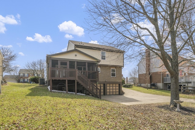 rear view of property featuring stairway, a lawn, a garage, a sunroom, and driveway